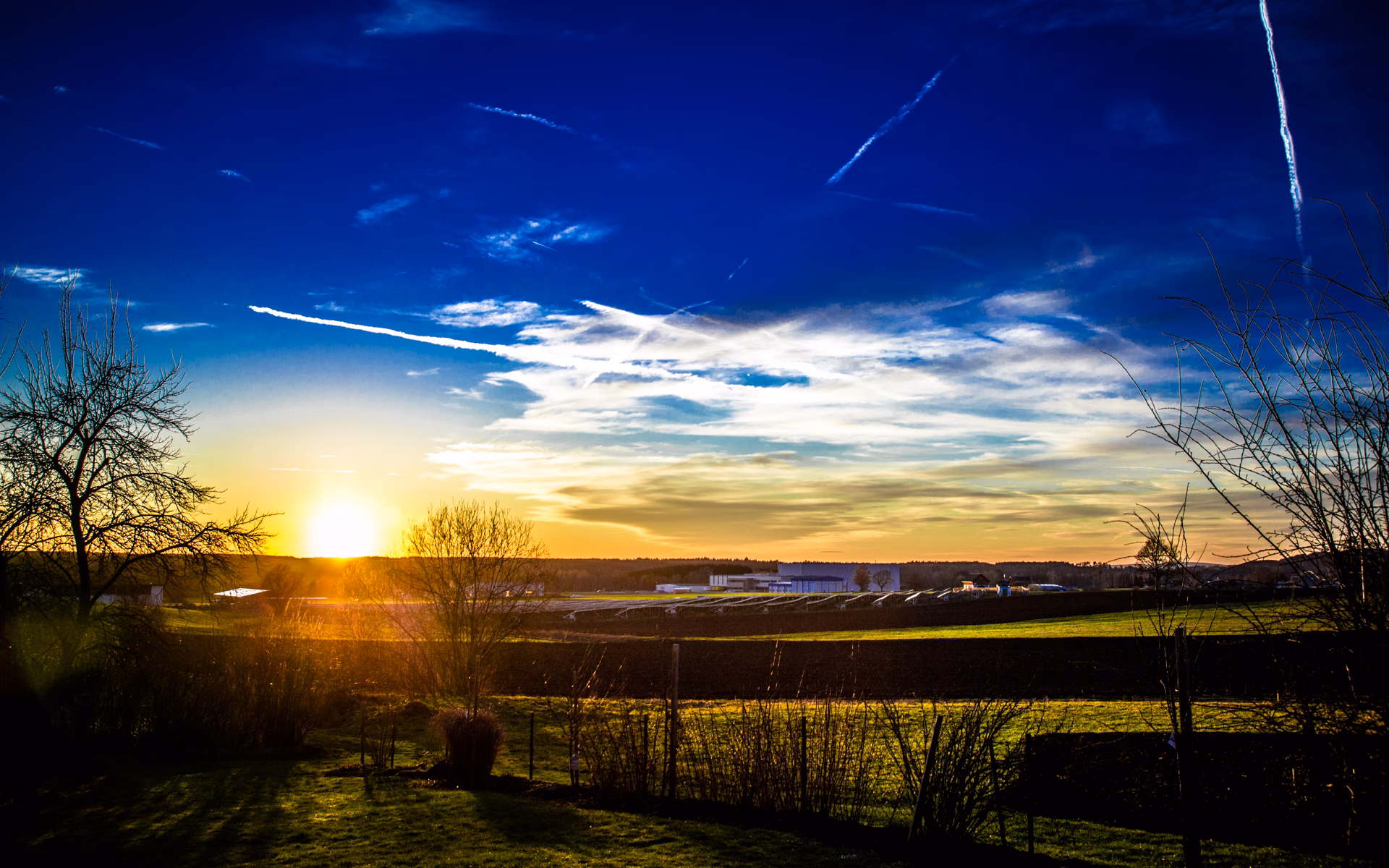 Surreal Sonnenuntergang mit Kondensstreifen über einem Feld